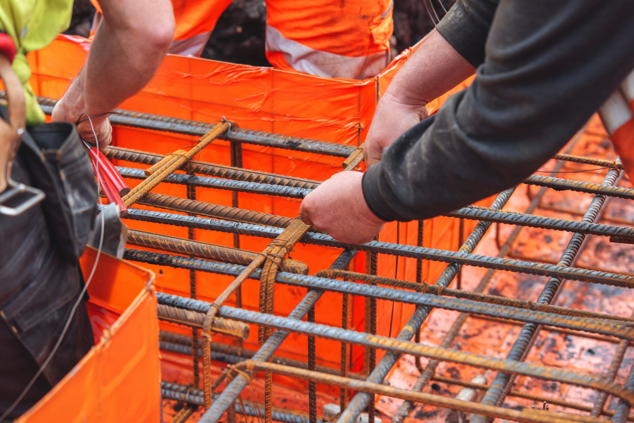 Close-up of steel fixer construction worker preparing and assembling reinforcement rebar on building site for concrete pouring project